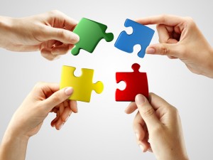 Hands and puzzle on gray background. Teamwork solving a puzzle